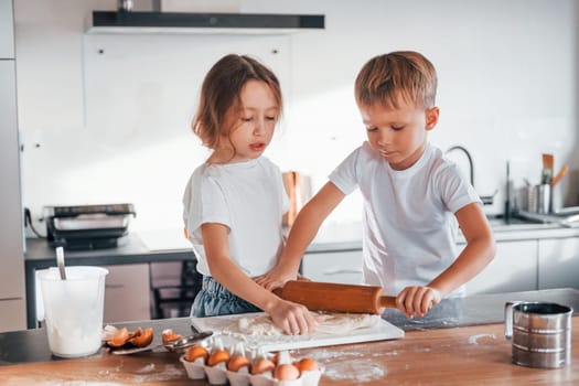 Two people together. Little boy and girl preparing Christmas cookies on the kitchen.