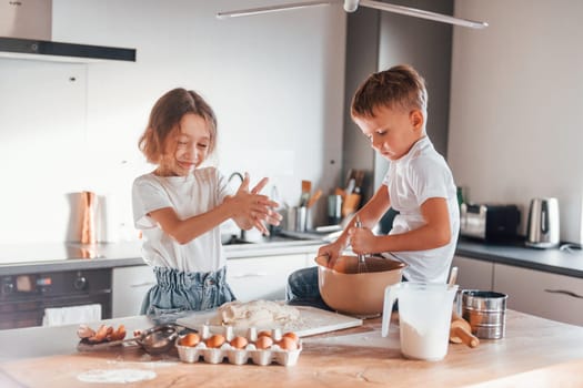 Making sweets. Little boy and girl preparing Christmas cookies on the kitchen.