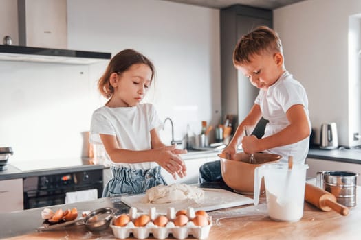 Making sweets. Little boy and girl preparing Christmas cookies on the kitchen.