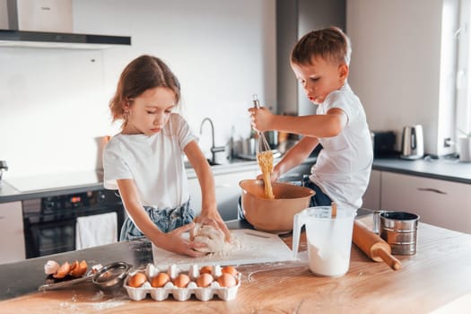 Making sweets. Little boy and girl preparing Christmas cookies on the kitchen.