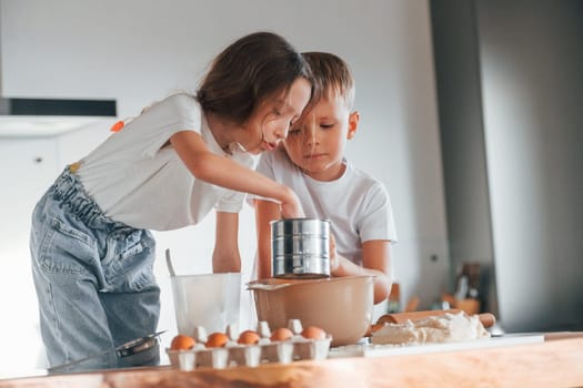 Pouring water. Little boy and girl preparing Christmas cookies on the kitchen.