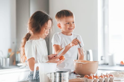 At daytime. Little boy and girl preparing Christmas cookies on the kitchen.