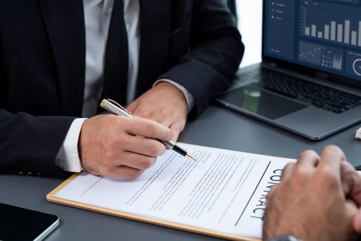 Closeup hand signing contract document with pen, sealing business deal with signature. Businesspeople finalizing business agreement by writing down signature on contract paper. Fervent