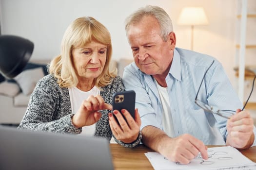 With laptop on the table. Senior man and woman is together at home.