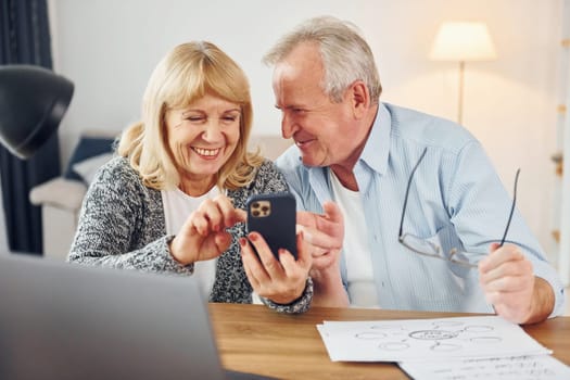 With modern laptop. Senior man and woman is together at home.