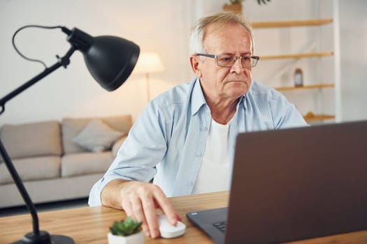 With laptop on table. Senior man in nice clothes is at home.