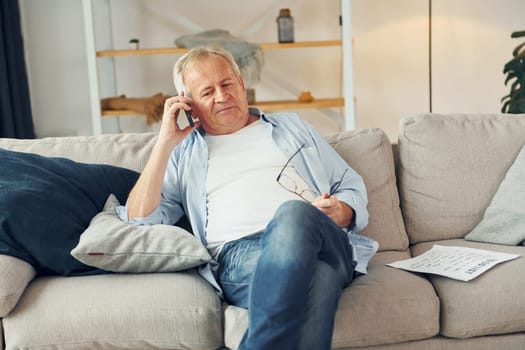 Talking by phone. Senior man in nice clothes is at home.