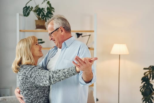 Dancing in the domestic room. Senior man and woman is together at home.