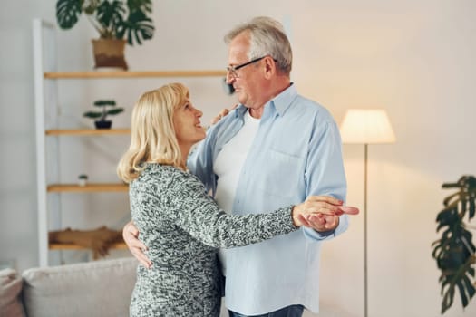 Dancing in the domestic room. Senior man and woman is together at home.