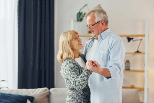 Dancing in the domestic room. Senior man and woman is together at home.