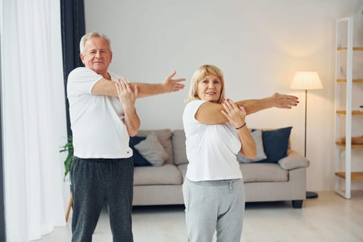 Sportive exercises. Senior man and woman is together at home.