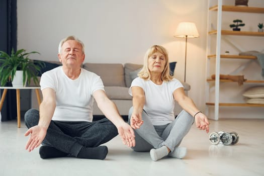 Doing yoga. Senior man and woman is together at home.