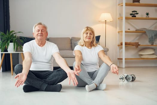 Doing yoga. Senior man and woman is together at home.