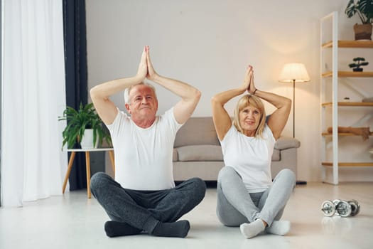 Doing yoga. Senior man and woman is together at home.