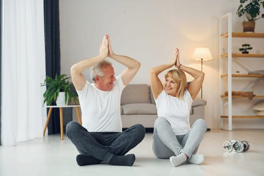 Doing yoga. Senior man and woman is together at home.