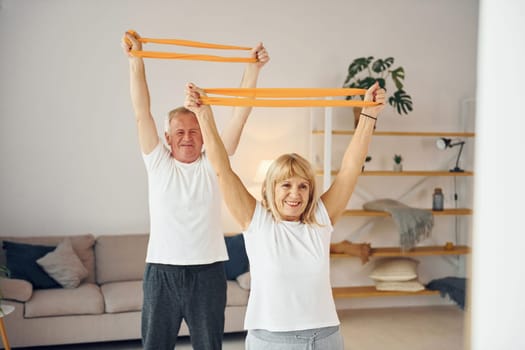 Doing stretching and fitness exercises. Senior man and woman is together at home.