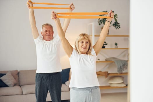 Doing stretching and fitness exercises. Senior man and woman is together at home.