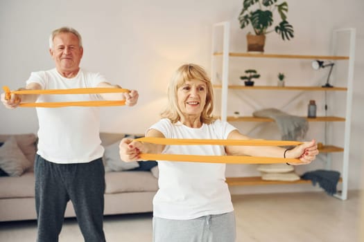 Doing stretching and fitness exercises. Senior man and woman is together at home.