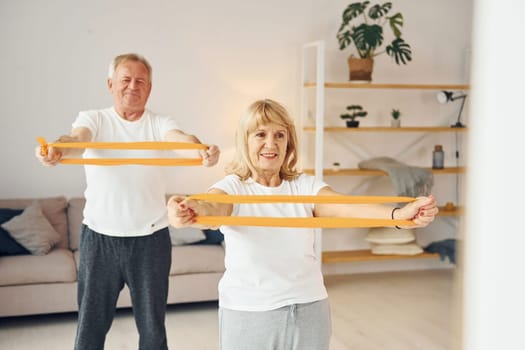 Doing stretching and fitness exercises. Senior man and woman is together at home.