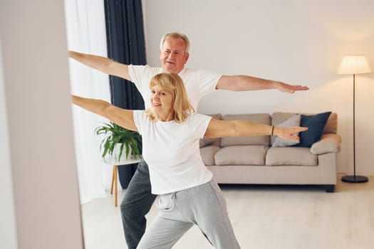 Sportive exercises. Senior man and woman is together at home.