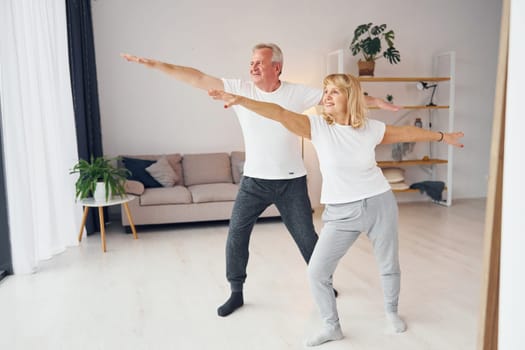 Sportive exercises. Senior man and woman is together at home.