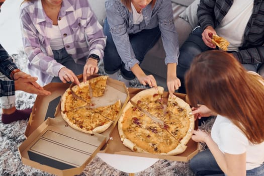 Eating delicious pizza. Group of friends have party indoors together.