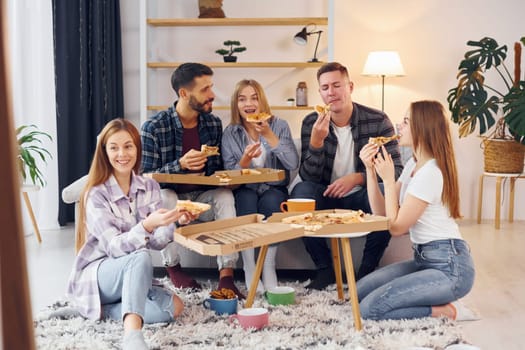Eating delicious pizza. Group of friends have party indoors together.