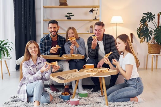Eating delicious pizza. Group of friends have party indoors together.