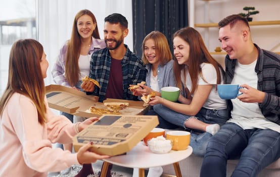 With cups of drink. Group of friends have party indoors together.