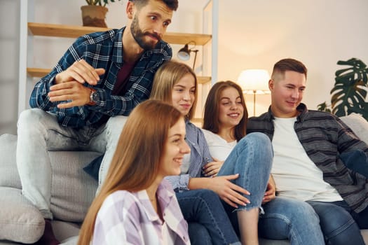 Sitting on the sofa. Group of friends have party indoors together.