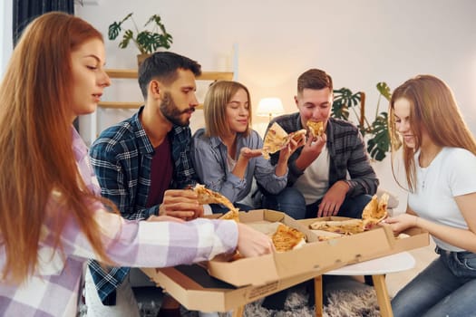 With delicious pizza. Group of friends have party indoors together.