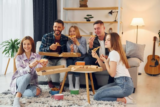 It's pizza time. Group of friends have party indoors together.