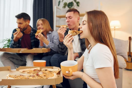 It's pizza time. Group of friends have party indoors together.