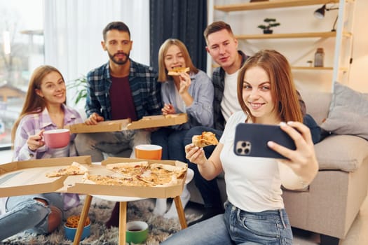 It's pizza time. Group of friends have party indoors together.