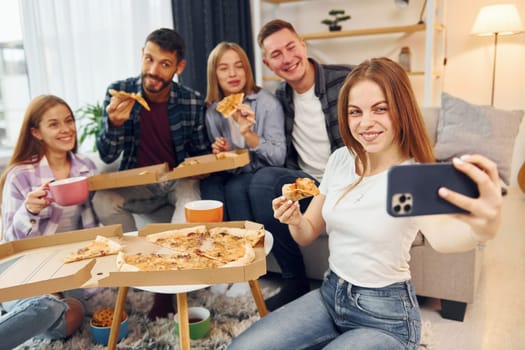 Making selfie photo. Group of friends have party indoors together.