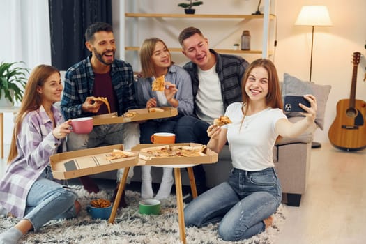 Making selfie photo. Group of friends have party indoors together.