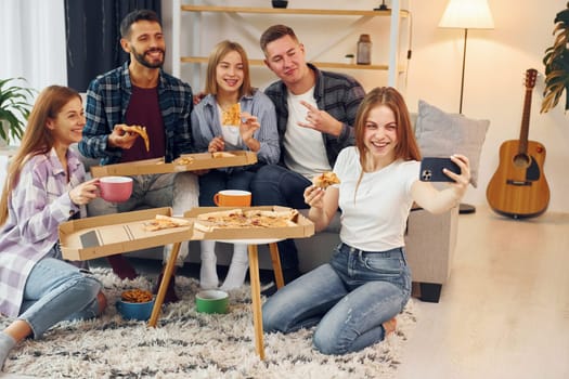 Making selfie photo. Group of friends have party indoors together.