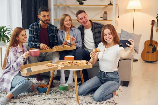 Making selfie photo. Group of friends have party indoors together.