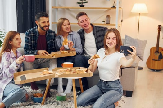 Making selfie photo. Group of friends have party indoors together.