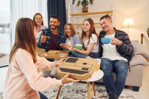 Eating food and drinking tea. Group of friends have party indoors together.