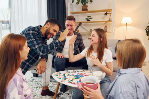 Playing smart game. Group of friends have party indoors together.