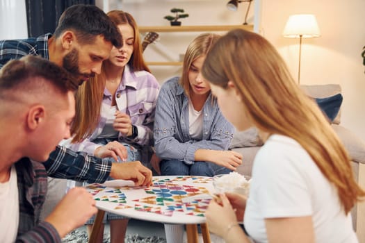 Playing smart game. Group of friends have party indoors together.