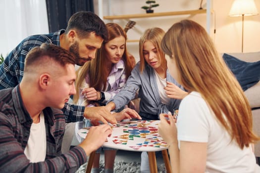 Playing smart game. Group of friends have party indoors together.