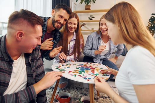 Playing smart game. Group of friends have party indoors together.