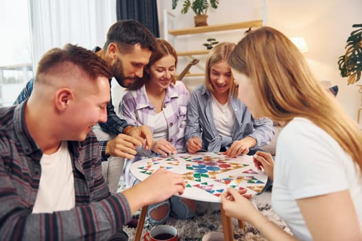 Puzzle game on the table. Group of friends have party indoors together.