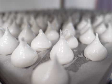 pastry chef baker artisan making white swirl and twirl meringue cones with piping bag filled with egg cream and sugar to bake for sweet preparation