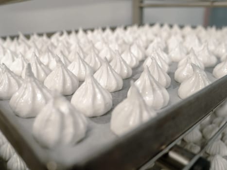 pastry chef baker artisan making white swirl and twirl meringue cones with piping bag filled with egg cream and sugar to bake for sweet preparation