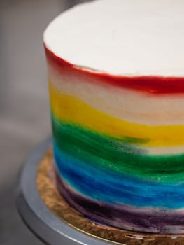 pastry chef working on a frosted cup cake with lgbt rainbow colours for wedding union party celebration. Birthday cupcake. Rainbow paper cup liners. Happy Birthday. Celebration Holidays. LGBT pride.