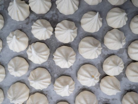 pastry chef baker artisan making white swirl and twirl meringue cones with piping bag filled with egg cream and sugar to bake for sweet preparation