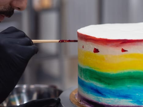 pastry chef working on a frosted cup cake with lgbt rainbow colours for wedding union party celebration. Birthday cupcake. Rainbow paper cup liners. Happy Birthday. Celebration Holidays. LGBT pride.